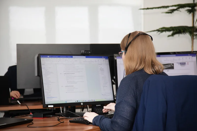 Technische Redakteurin arbeitet an Softwaredokumentation mit zwei Monitoren und Headset
